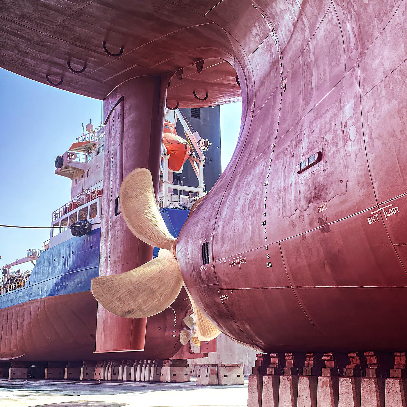 Eine Schiffsschraube eines Schiffes in einer Werft mit einem weiteren Schiff im Hintergrund