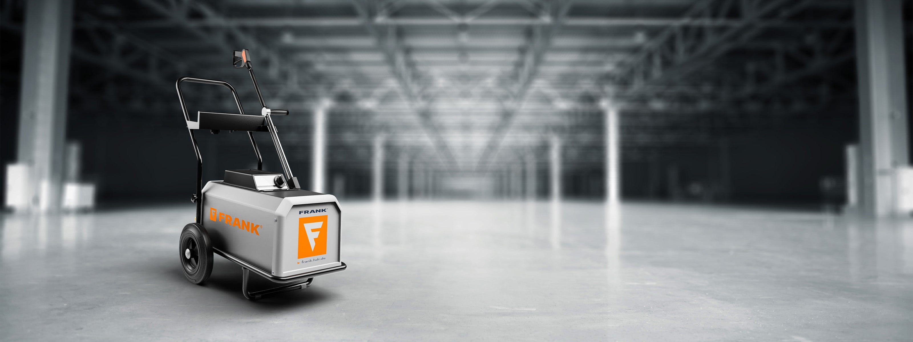 Ein mobiler FRANK Kaltwasserhochdruckreiniger steht in einer leeren Industriehalle