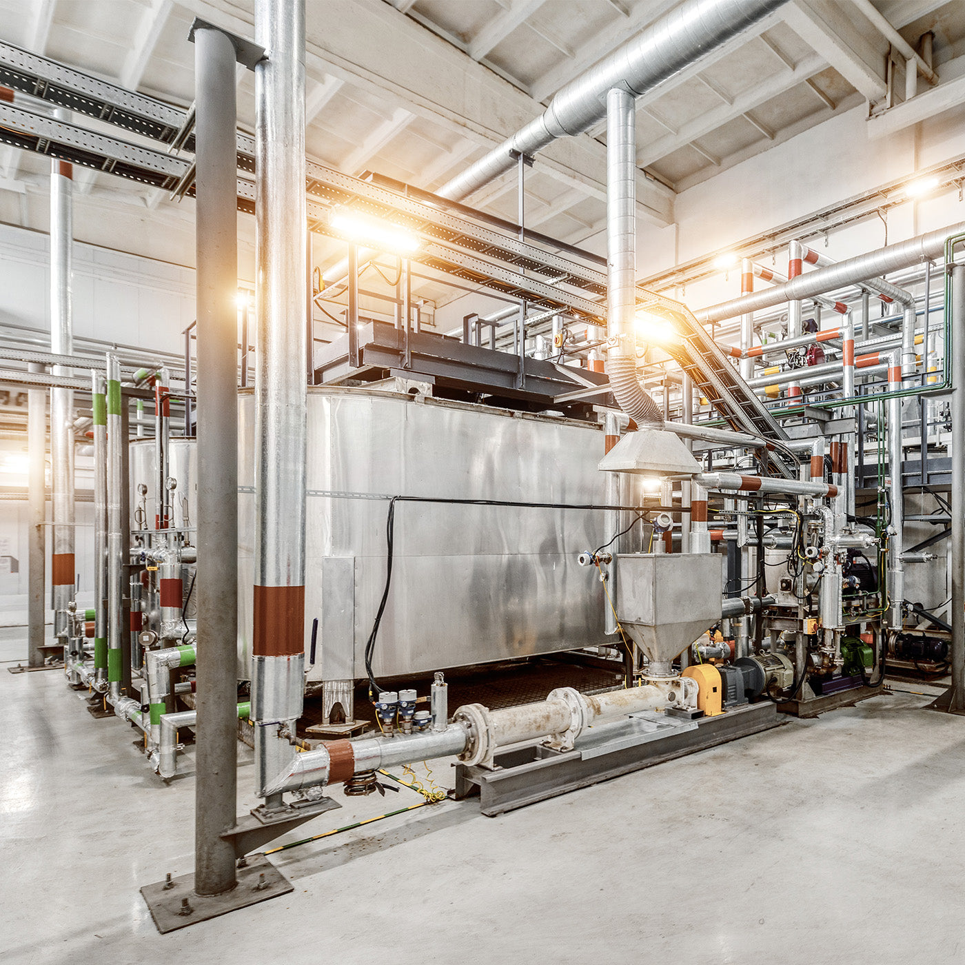 Eine große maschinelle Anlage mit vielen Verbindungsrohren steht in einer Industriehalle